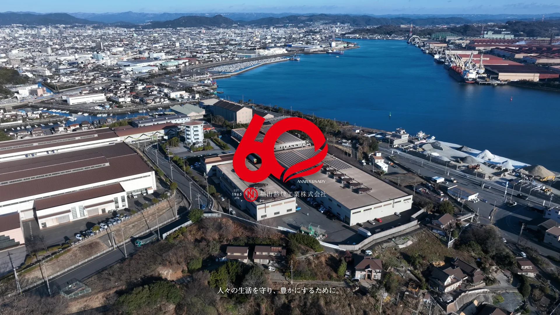 60周年ロゴを重ねた本社・工場の空撮エンドカット